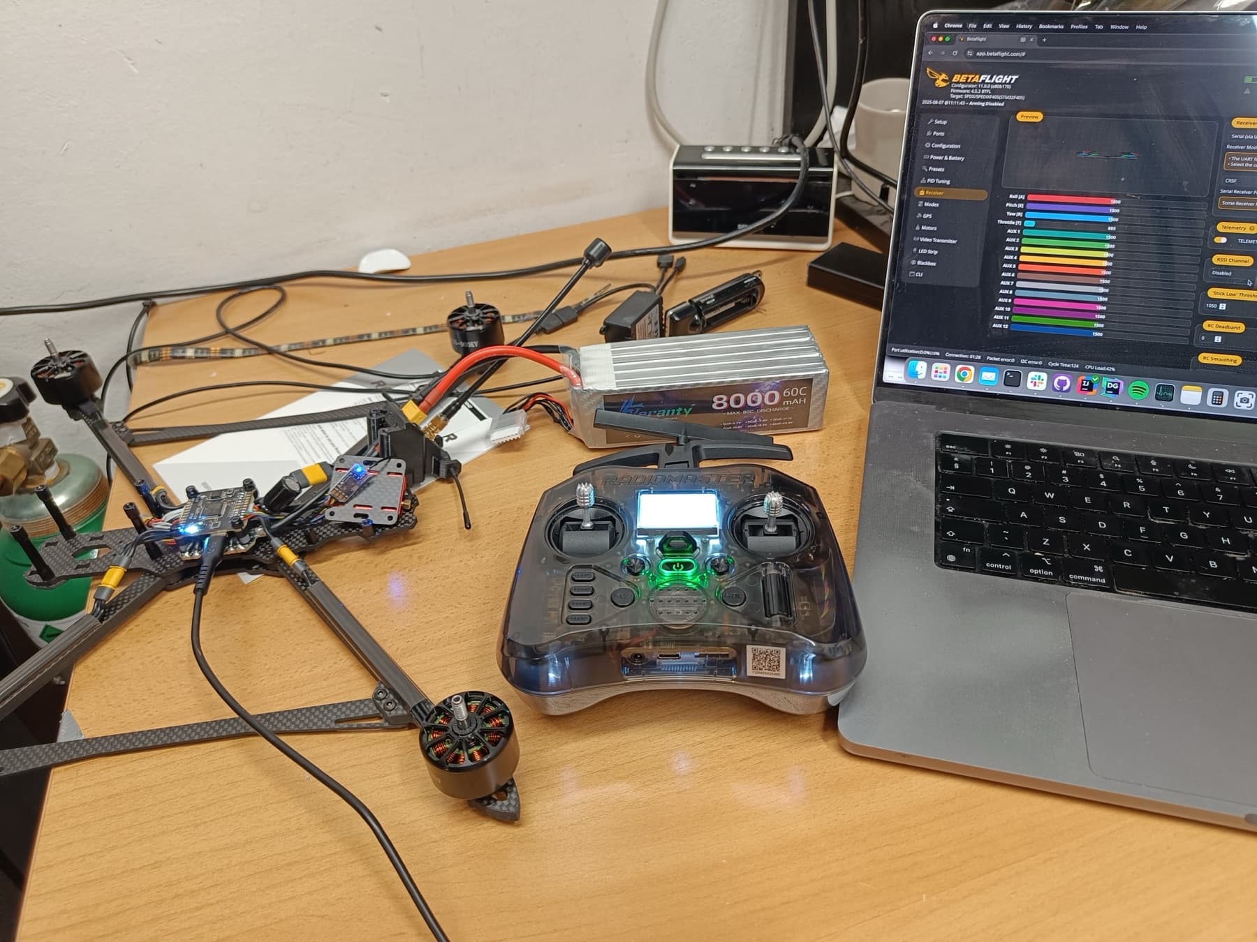 Drone, battery, radio controller, and laptop running flight-controller configuration software on a workbench