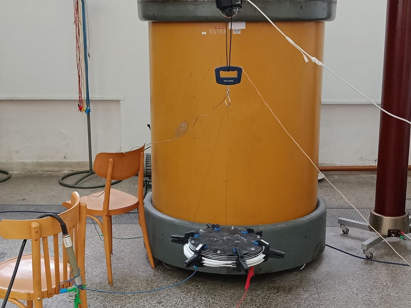 SCQ electrode stack suspended from a dynamometer beneath high-voltage laboratory equipment
